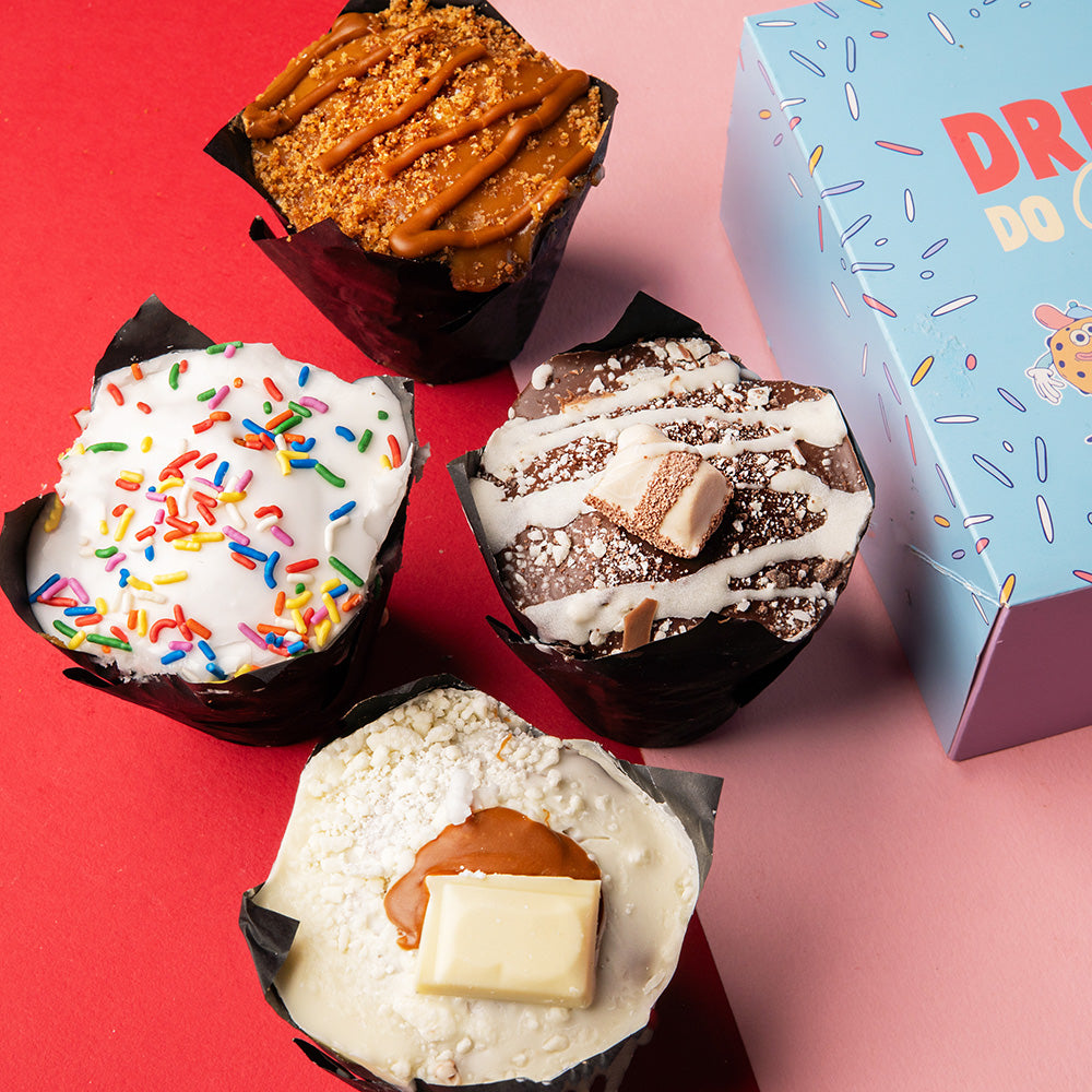 Assorted Mother’s Day muffins with  4 muffins, one containing a white chocolate drizzle on and bueno, one with a caramel topping, white with a white chocolate topping and milkybar and one with a vanilla icing and sprinkles. 