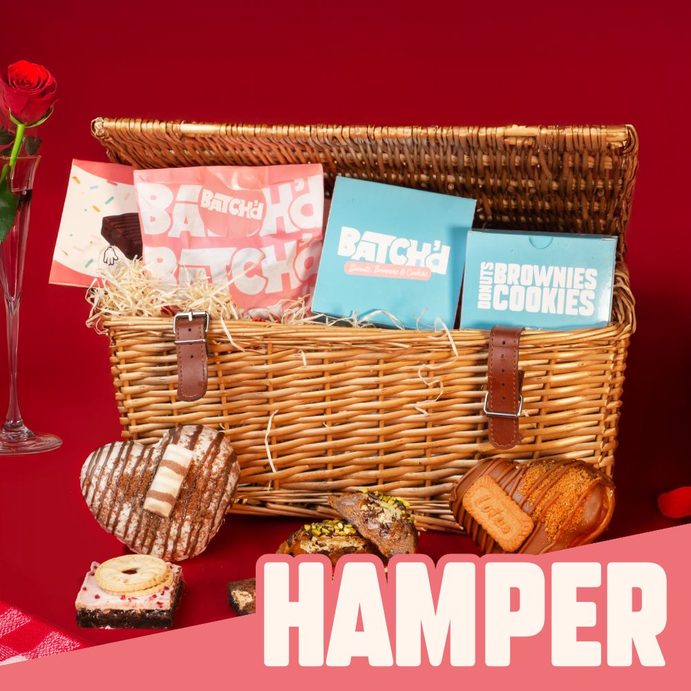 A wicker basket with Valentines treat such as 2 heart shaped donuts, one bueno flavoured and one biscoff flavoured, 1 pistachio cookie and 4 brownies.
