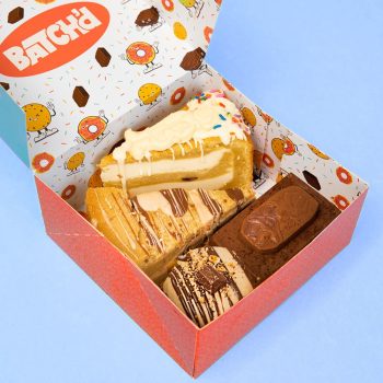 A gift box full of sweet treats with a Milkybar cookie pie slice, nutella and kinder cookie pie slice, kinder stuffed cookie and a freddo brownie slab.